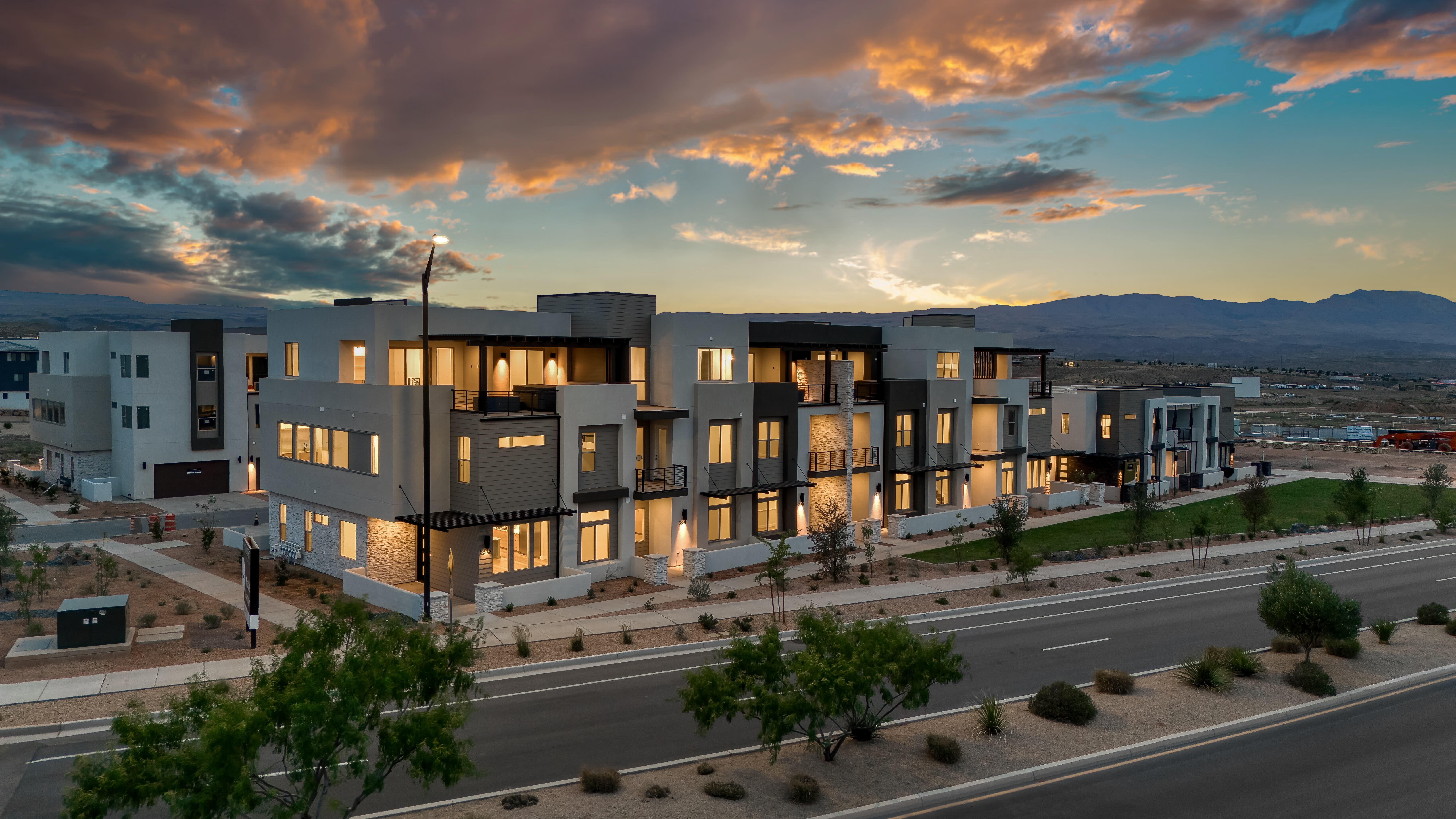 Twilight exterior of multiple Isle townhome units by Cole West — the uniform architecture that makes interior design the competitive differentiator at The Isles